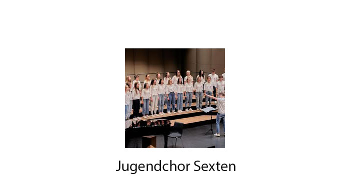 Ein Jugendchor tritt auf der Bühne auf, geleitet von einem Dirigenten; auf dem Schild steht „Jugendchor Sexten“. - HJPA Pro